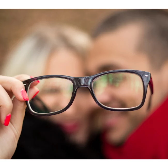 visage femme et homme floue et paire de lunette en premier plan
